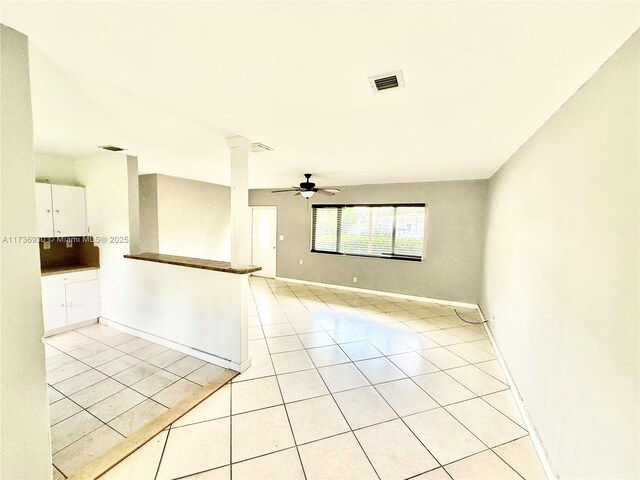 tiled spare room with ceiling fan and decorative columns