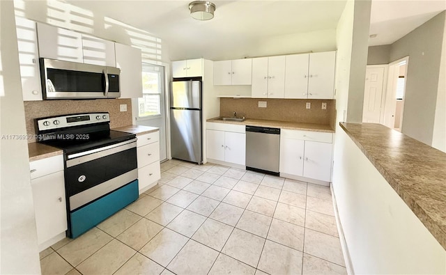 kitchen with tasteful backsplash, appliances with stainless steel finishes, white cabinets, and light tile patterned flooring