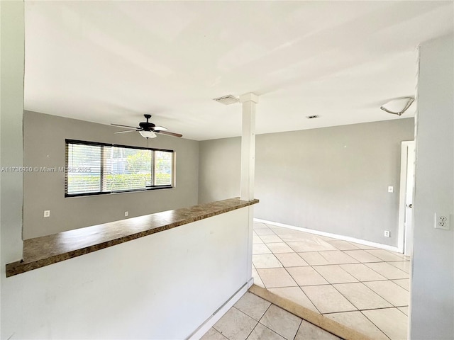 empty room with baseboards, visible vents, a ceiling fan, and light tile patterned flooring