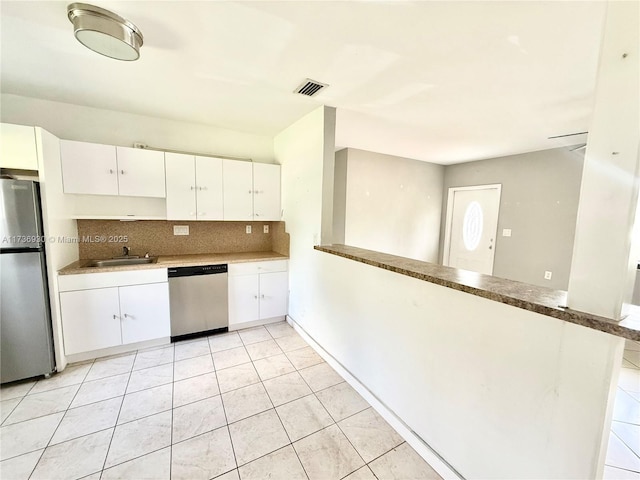 kitchen with stainless steel appliances, tasteful backsplash, visible vents, white cabinetry, and a sink