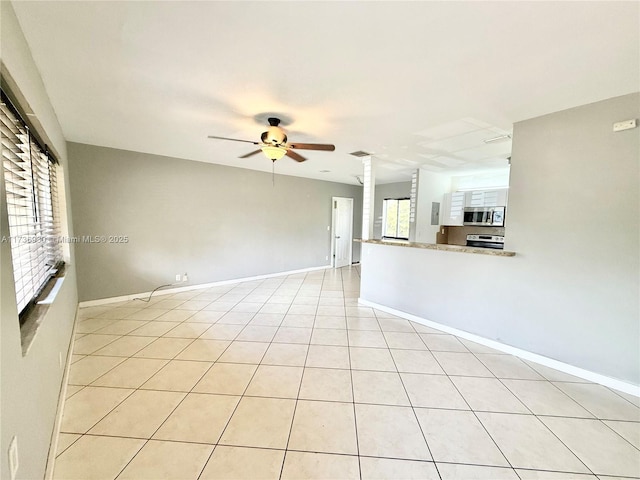 unfurnished room with ceiling fan, decorative columns, baseboards, and light tile patterned flooring