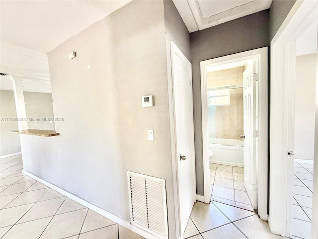 hallway with light tile patterned floors, baseboards, visible vents, and ornate columns