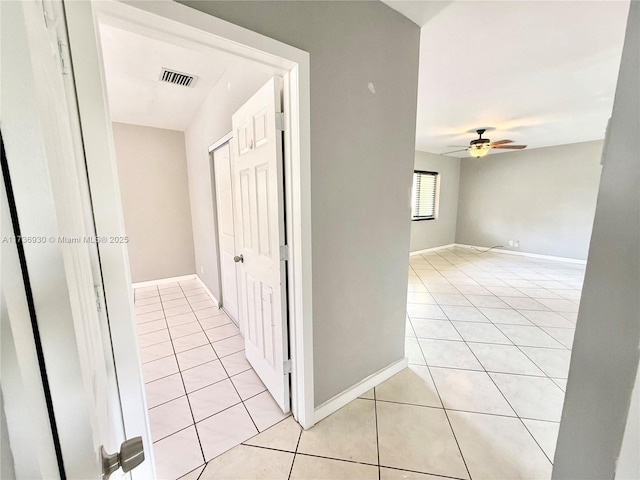 corridor featuring baseboards, visible vents, and light tile patterned flooring