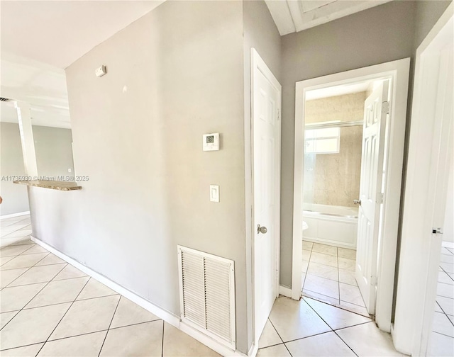 corridor featuring light tile patterned floors, decorative columns, visible vents, and baseboards