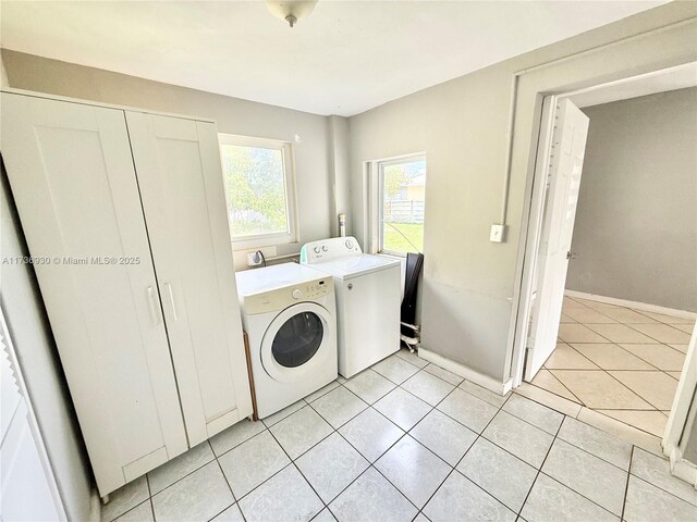 washroom with separate washer and dryer, light tile patterned floors, and cabinets