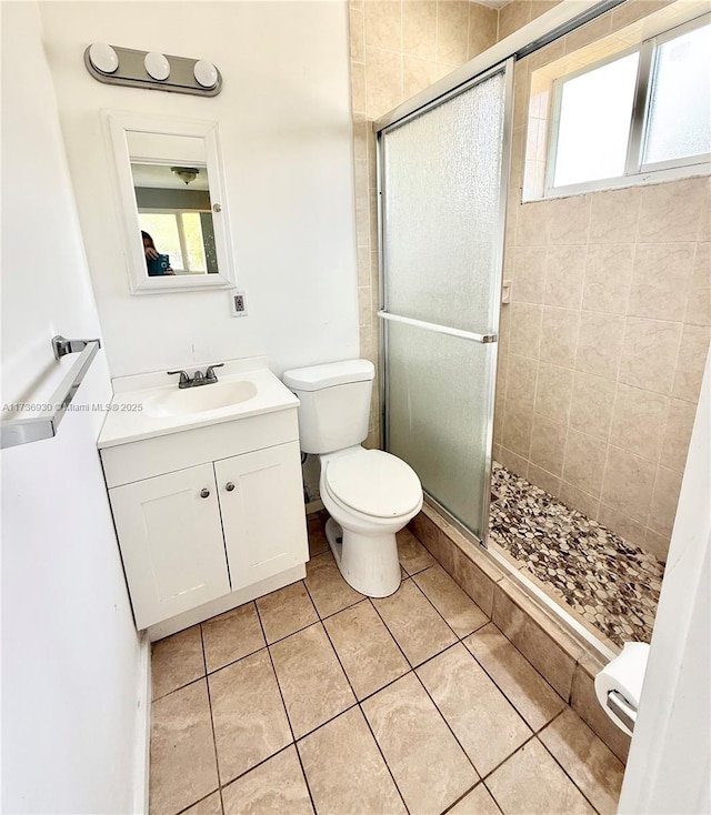 bathroom featuring a shower with door, vanity, tile patterned flooring, and toilet