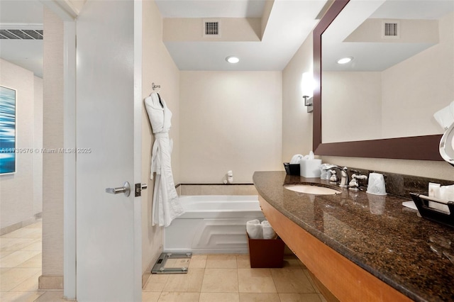 bathroom with tile patterned floors, a bathing tub, and vanity