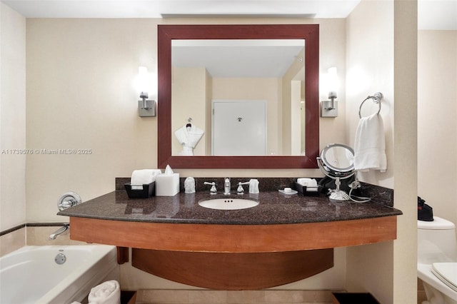 bathroom featuring vanity, a tub to relax in, and toilet