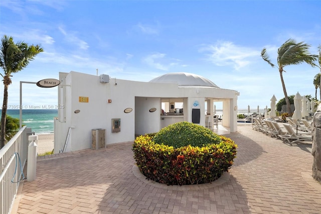 view of property's community featuring a water view, a view of the beach, and a patio