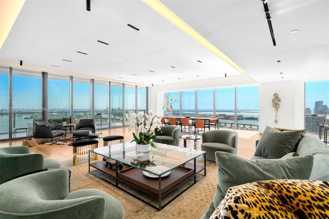 living room with light wood-type flooring, floor to ceiling windows, and a water view