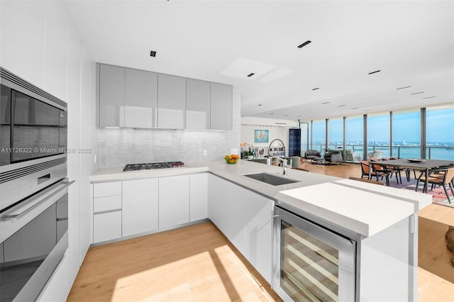 kitchen with sink, tasteful backsplash, appliances with stainless steel finishes, kitchen peninsula, and beverage cooler