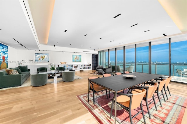 dining room with a water view, expansive windows, and light wood-type flooring