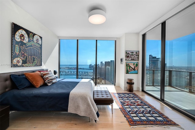 bedroom featuring floor to ceiling windows, access to exterior, and wood-type flooring