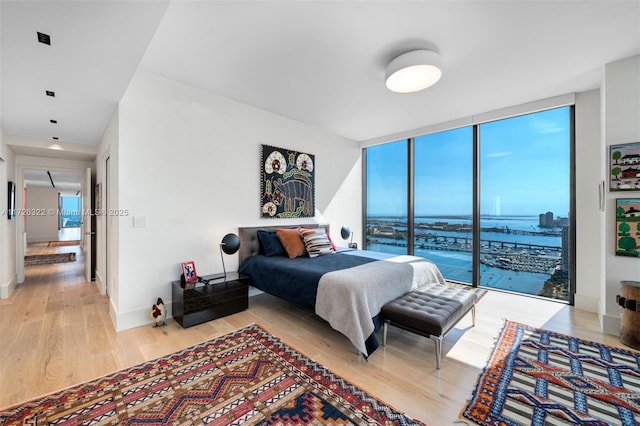 bedroom with expansive windows, access to exterior, and light hardwood / wood-style flooring