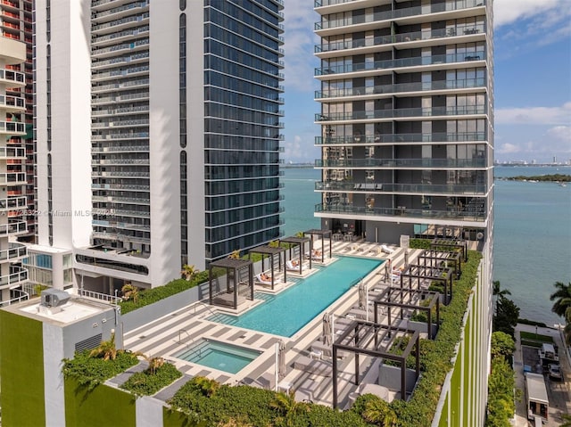 view of pool featuring a community hot tub, a water view, and a patio