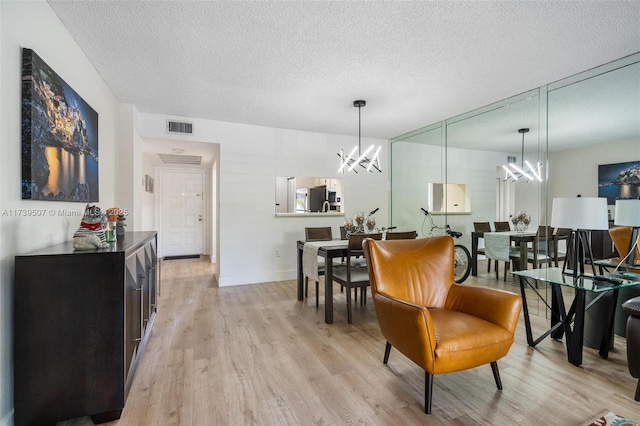 dining space featuring an inviting chandelier, light hardwood / wood-style flooring, and a textured ceiling