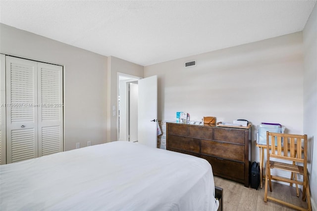 bedroom featuring light hardwood / wood-style floors, a closet, and a textured ceiling