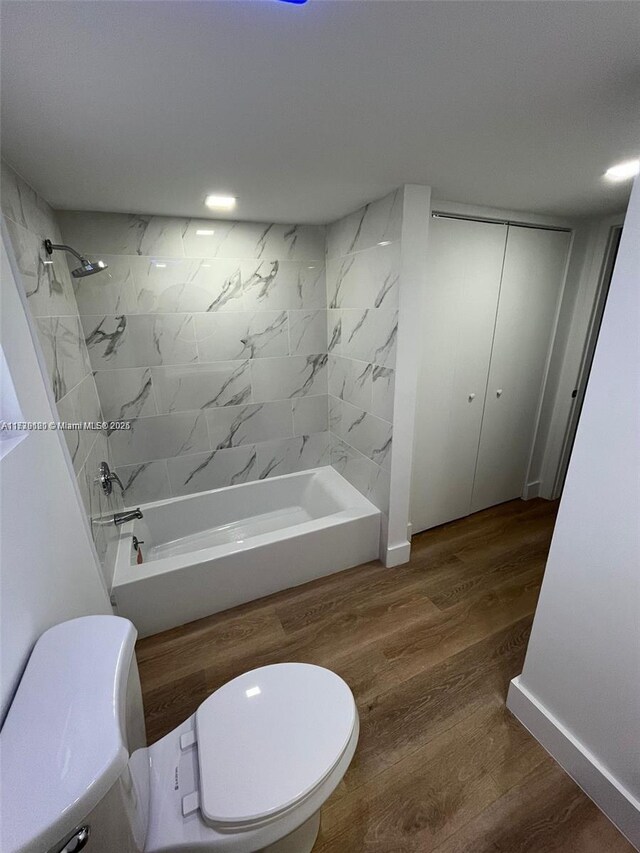 bathroom featuring hardwood / wood-style floors, tiled shower / bath, and toilet