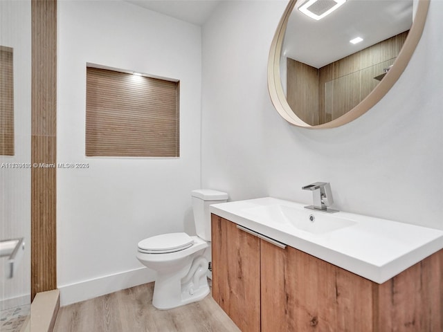 bathroom featuring vanity, wood-type flooring, and toilet