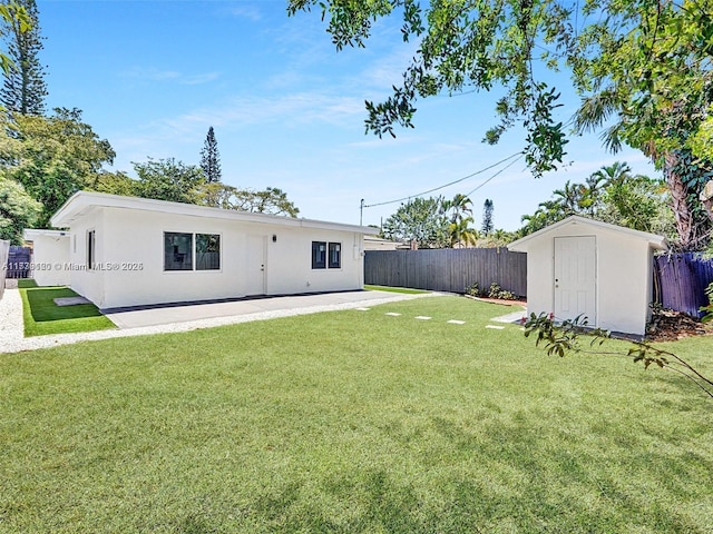 back of property with a lawn, a patio area, and a storage shed