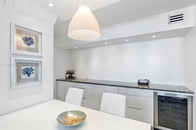 kitchen featuring pendant lighting, sink, white cabinetry, and beverage cooler