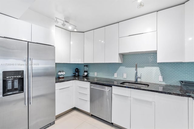 kitchen featuring white cabinetry, stainless steel appliances, sink, and dark stone counters