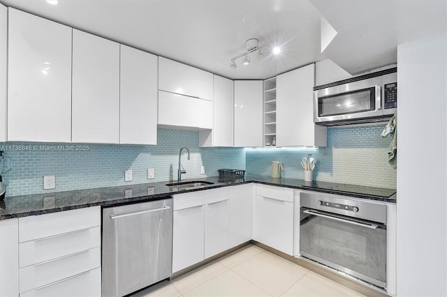 kitchen featuring light tile patterned flooring, sink, white cabinetry, dark stone countertops, and appliances with stainless steel finishes