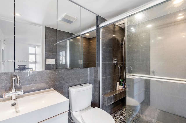 bathroom with an enclosed shower, vanity, toilet, and tile walls