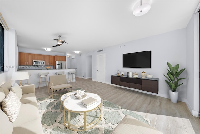 living room with ceiling fan and light wood-type flooring