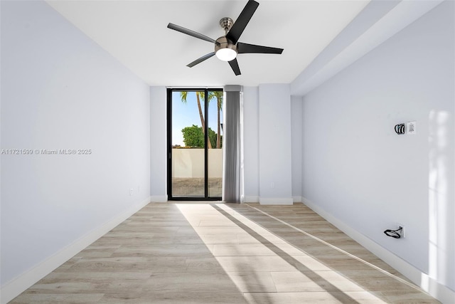 empty room featuring ceiling fan, floor to ceiling windows, and light wood-type flooring