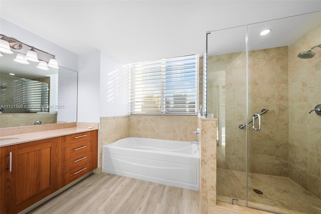 bathroom with independent shower and bath, wood-type flooring, and vanity