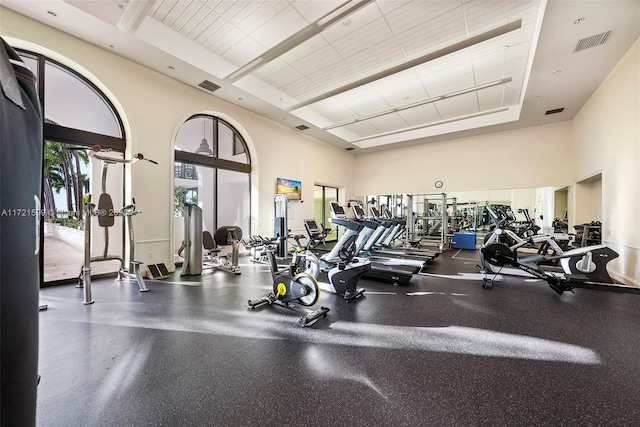 gym with a high ceiling and a tray ceiling