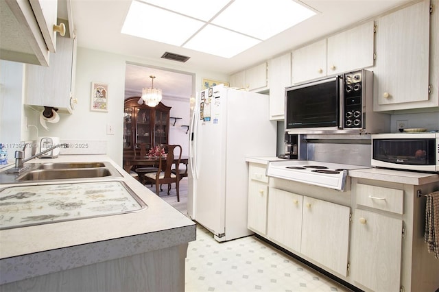 kitchen with a notable chandelier, cooktop, sink, and white fridge with ice dispenser