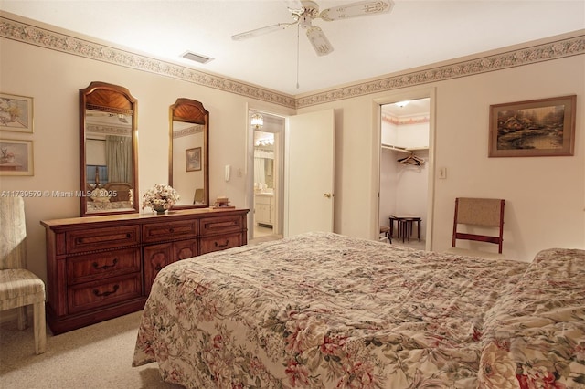 carpeted bedroom featuring ceiling fan, ensuite bathroom, and a spacious closet