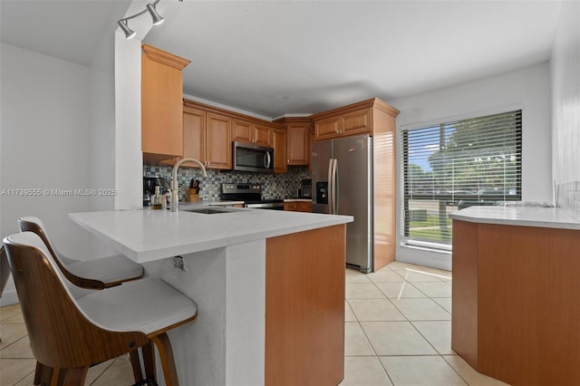 kitchen with a breakfast bar, appliances with stainless steel finishes, kitchen peninsula, and sink