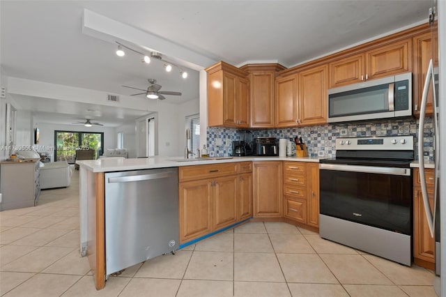 kitchen featuring appliances with stainless steel finishes, sink, light tile patterned floors, and decorative backsplash