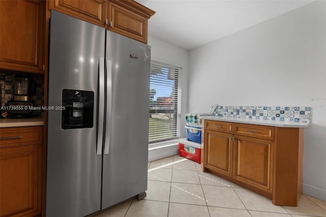 kitchen with stainless steel refrigerator with ice dispenser, tasteful backsplash, and light tile patterned floors