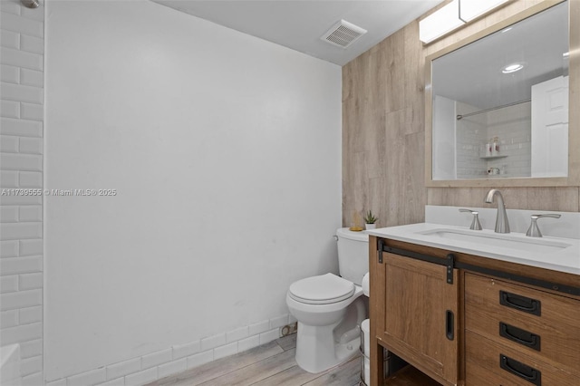 bathroom with hardwood / wood-style flooring, vanity, a shower, and toilet