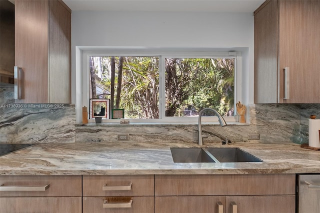 kitchen featuring tasteful backsplash, a healthy amount of sunlight, light stone countertops, and sink