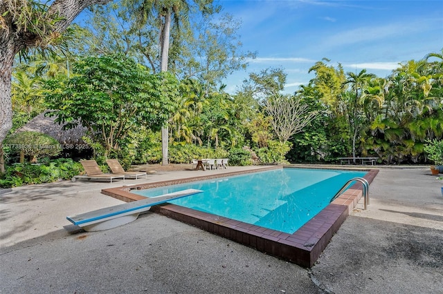 view of pool featuring a diving board and a patio