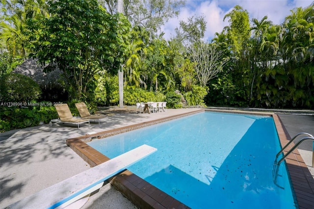 view of pool with a patio and a diving board