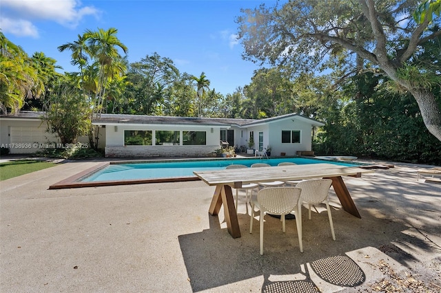 view of pool with a diving board and a patio area