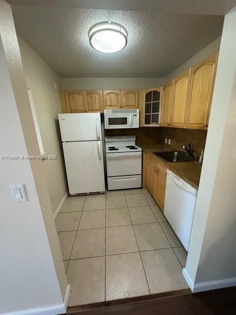 kitchen featuring sink, white appliances, light tile patterned floors, a textured ceiling, and light brown cabinetry