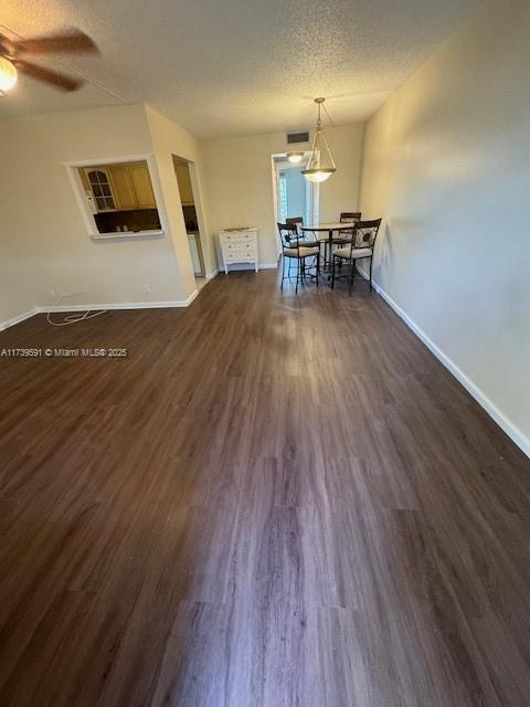 unfurnished dining area with ceiling fan, dark hardwood / wood-style floors, and a textured ceiling