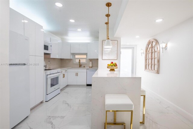 kitchen with sink, white appliances, white cabinetry, decorative backsplash, and decorative light fixtures