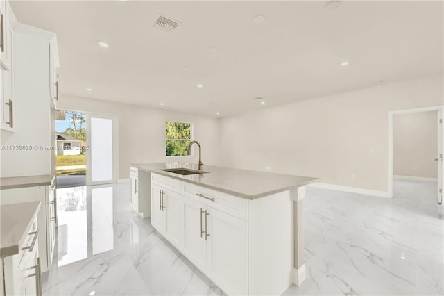 kitchen featuring white cabinetry, sink, and a center island with sink