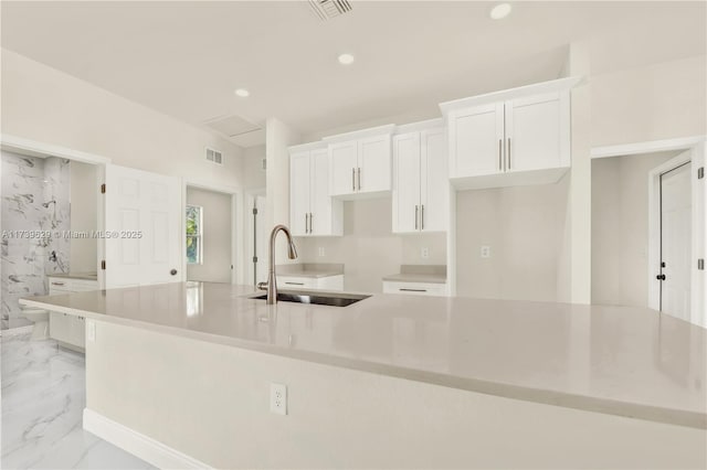 kitchen featuring white cabinetry, sink, and a kitchen island