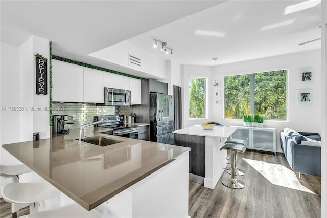 kitchen featuring sink, a breakfast bar, stainless steel appliances, white cabinets, and kitchen peninsula