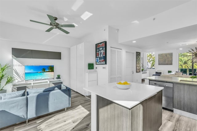 kitchen featuring ceiling fan, stainless steel dishwasher, a kitchen island, and light hardwood / wood-style flooring