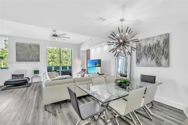 dining space with ceiling fan with notable chandelier, a healthy amount of sunlight, and hardwood / wood-style floors